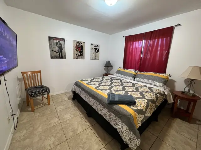 King bedroom with smart TV and red curtains