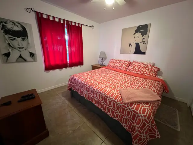 King bedroom with red geometric bedding and red curtains